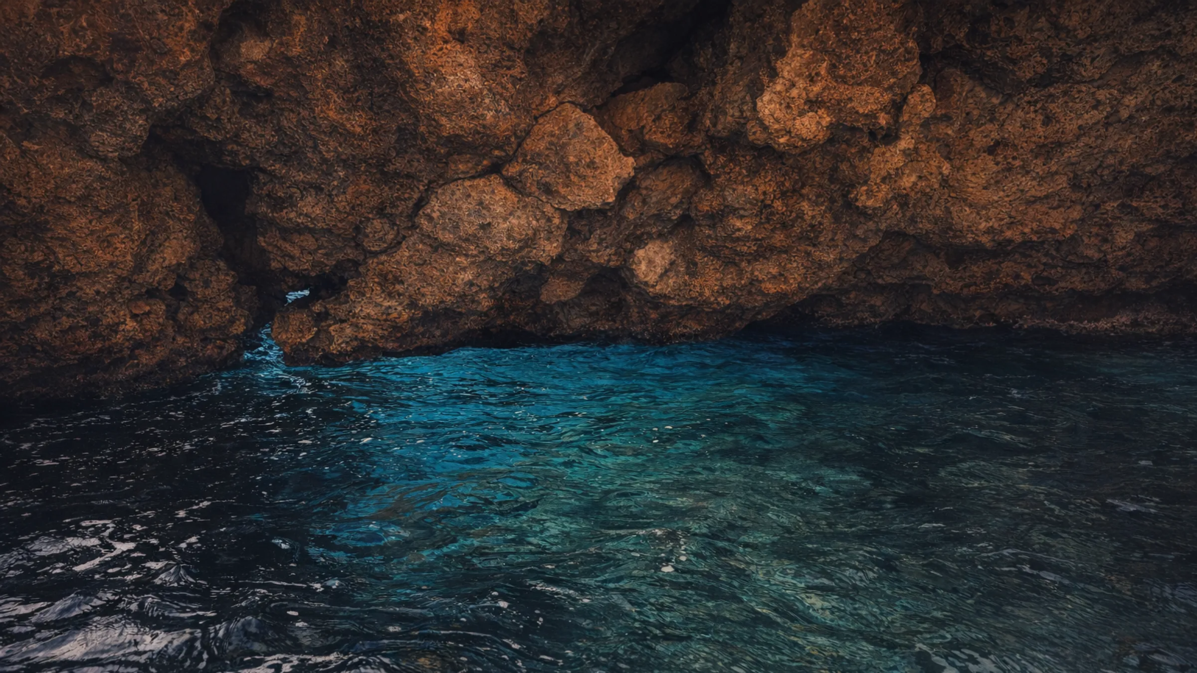 Sea cave with glowing turquoise water under a rock overhang